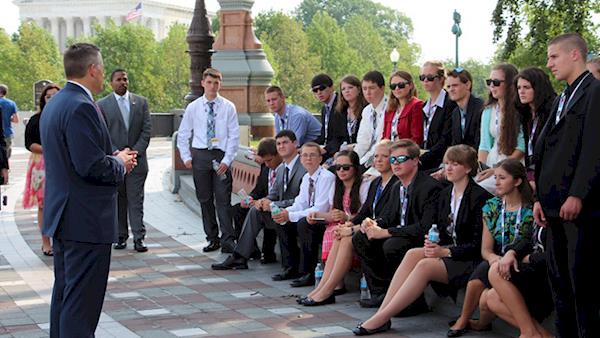 Youth Education Summit attendees listening to a speech outdoors.